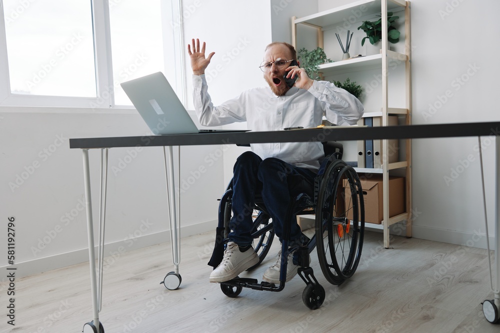A man in a wheelchair a businessman with tattoos in the office works, talking on the phone, anger and aggression, integration into society, the concept of working a person with disabilities A man in a wheelchair a businessman with tattoos in the office works, talking on the phone, anger and aggression, integration into society, the concept of working a person with disabilities