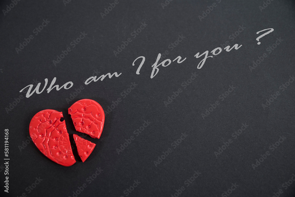 Złamane czerwone serce na czarnym tle z napisem "Who am I for you". - obrazy, fototapety, plakaty 