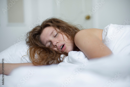 young girl sleeps in the morning in bed and snores loudly with her mouth open, the concept of person have problem with sleep and breathing