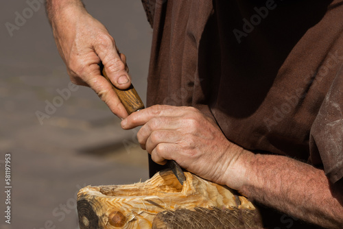 Carpenter carving a hole in the wood of a clog.
