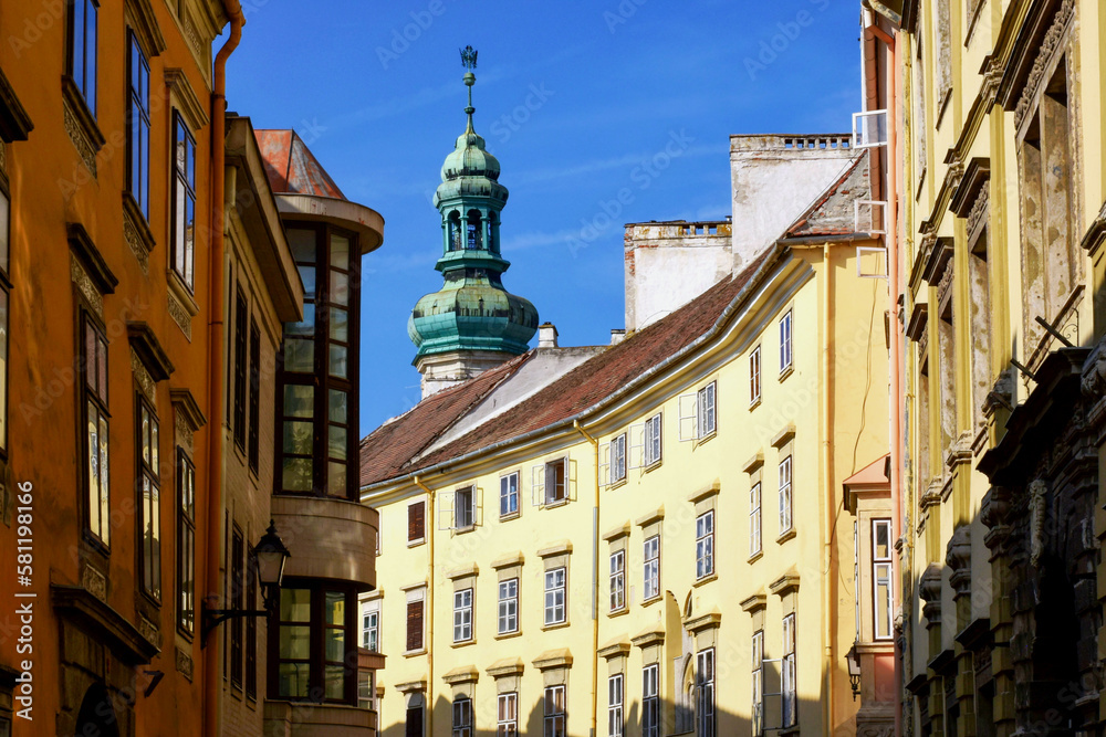 Famous old historic fire watch tower in the city of Sopron, Hungary. green copper cupola with air vane or eagle cock. popular landmark and tourist attraction. low angle perspective streetscape view