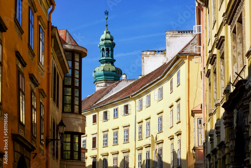 Famous old historic fire watch tower in the city of Sopron, Hungary. green copper cupola with air vane or eagle cock. popular landmark and tourist attraction. low angle perspective streetscape view