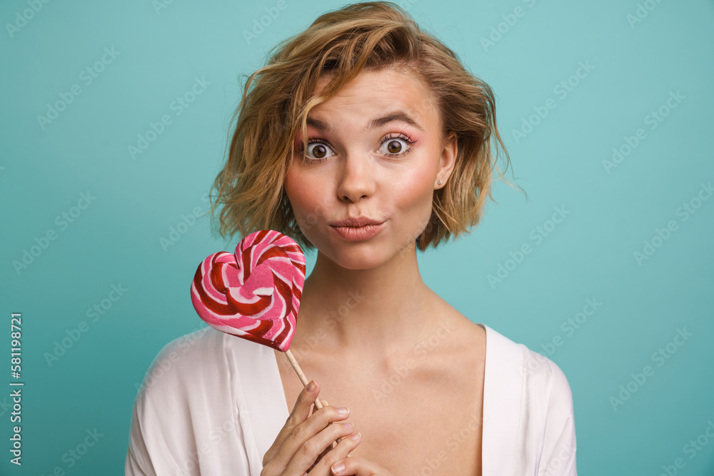 Beautiful woman posing with lollipop isolated over blue background Beautiful woman posing with lollipop isolated over blue background