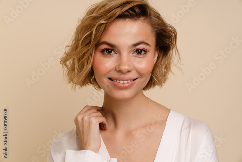 Woman smiling while standing isolated over beige background