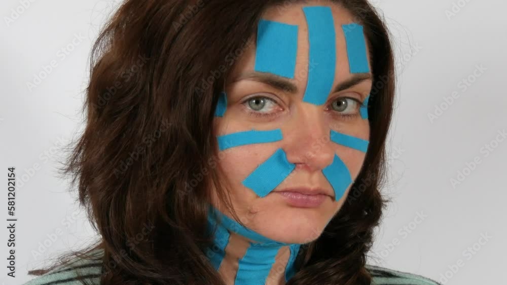 Young woman applied light blue kinesio strips taping face, forehead