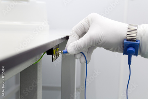 Bracelet on the hand of a man wearing ESD cloth and glove static resistance ESD bracelet or ground equipment, anti-static, used to safely ground is working. Semiconductor manufacturing.