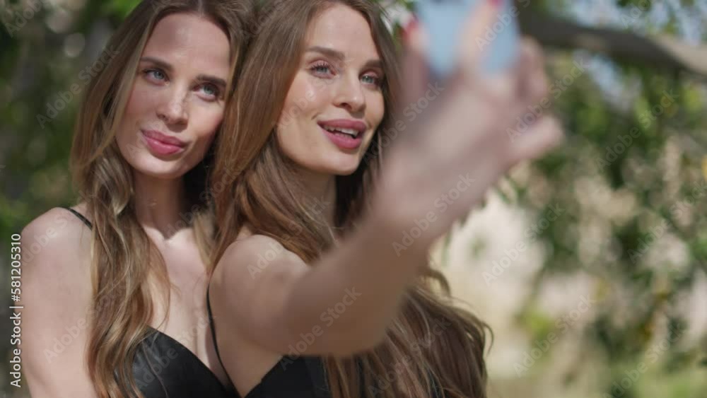 Identical twins with mobile phone for selfies Identical twins with mobile phone for selfies