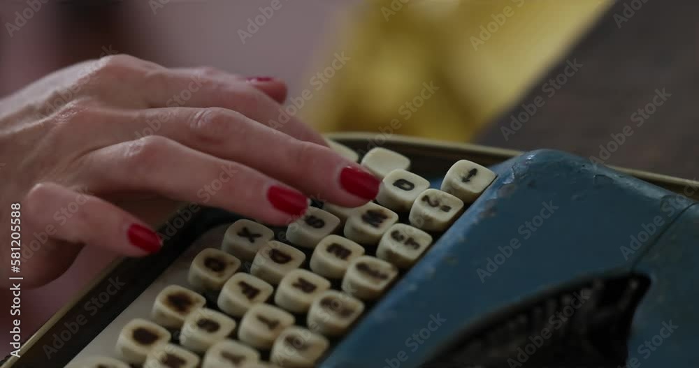 The woman is typing a text on an old blue typewriter. The woman is typing a text on an old blue typewriter.