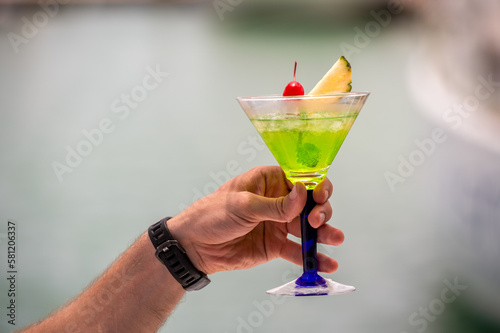 colorful gin tonic cocktails in glasses on on hand in yacht and sea background. hand cheers glass of cocktails cool drinks or Mocktail blended fruit margaritas, passionfruit drinks.