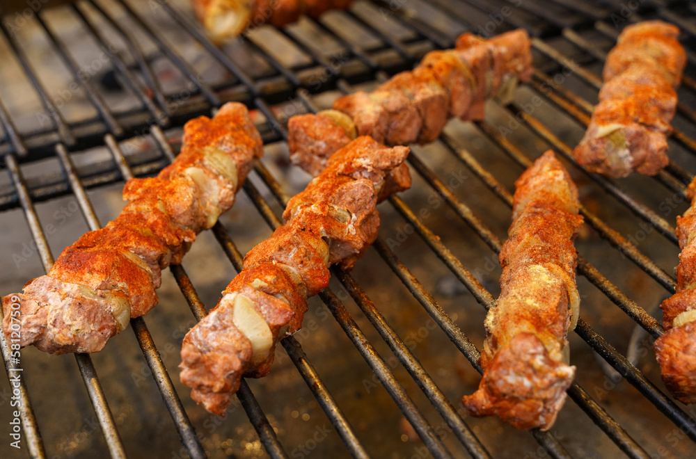 Fried meat with onions on a skewer lies on the grate. Polish street food Fried meat with onions on a skewer lies on the grate. Polish street food