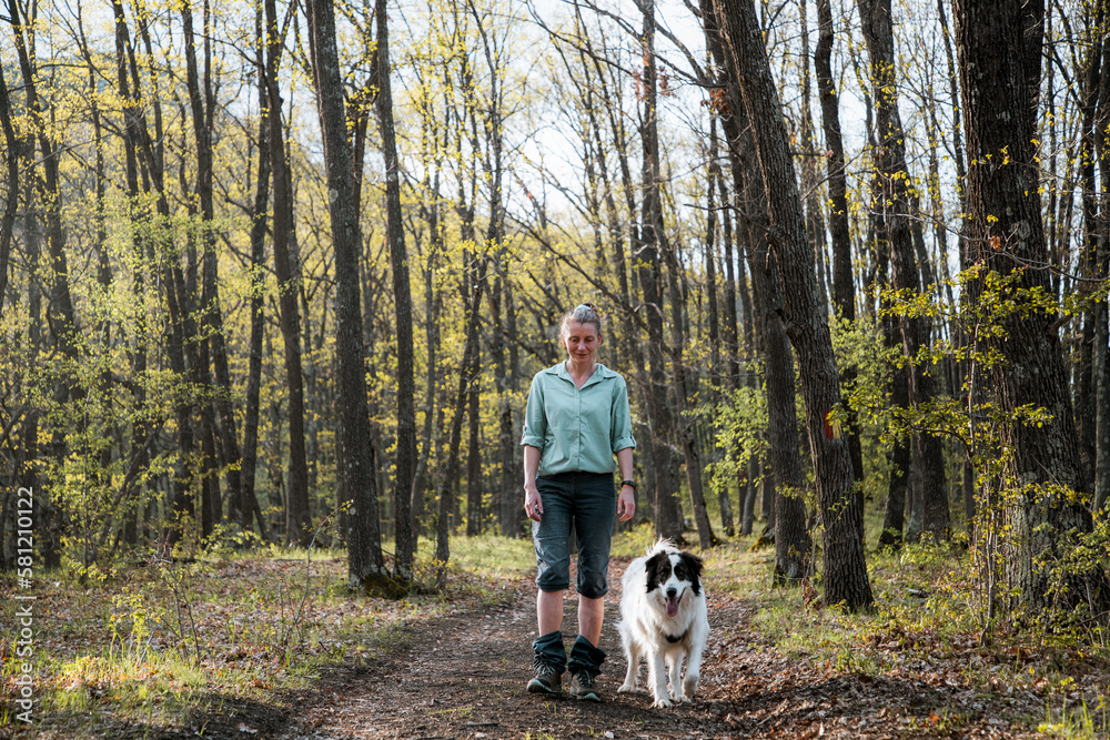 woman trekking in forest with dog woman trekking in forest with dog