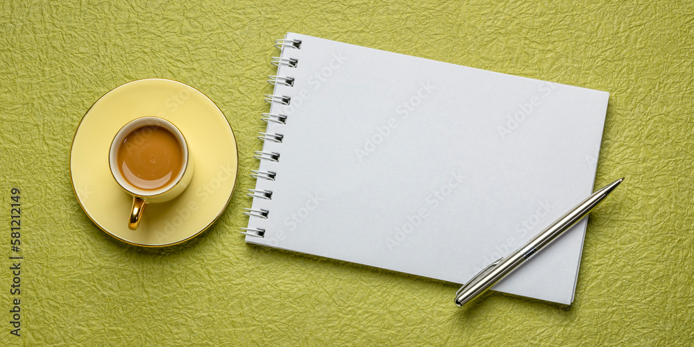blank spiral sketchbook against textured paper with a cup of coffee, desktop flat lay