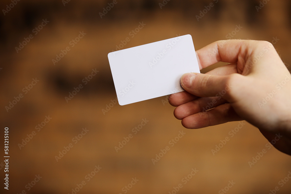 Male hand holds blank white card mockup on brick wall background. Plain call-card mock up template holding arm. Plastic credit namecard display front. Check offset card design. Business branding. Male hand holds blank white card mockup on brick wall background. Plain call-card mock up template holding arm. Plastic credit namecard display front. Check offset card design. Business branding.