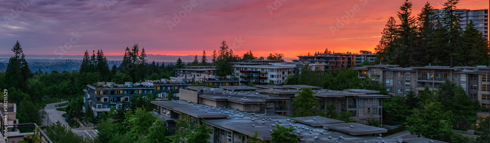 Fototapeta premium Stunning panoramic sunset over rooftops of homes in UniverCity Highlands, Burnaby, BC, as seen from a neighborhood patio.