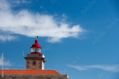 old lighthoiuse with red roof in front of blue sky in the south