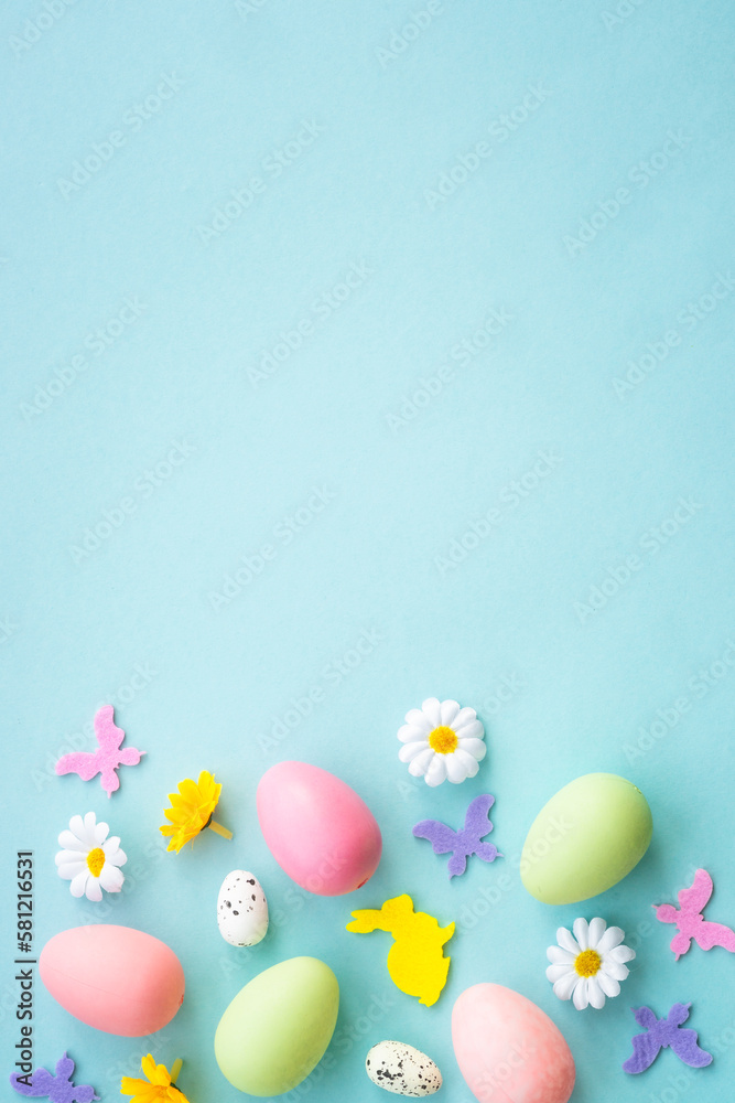 Easter background on blue. Eggs, rabbit, spring flowers and butterfly. Flat lay with copy space.