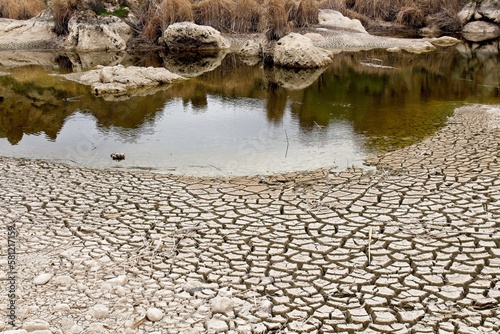 Cracked soil on the shore of a lake that's drying up. Shows climate change.