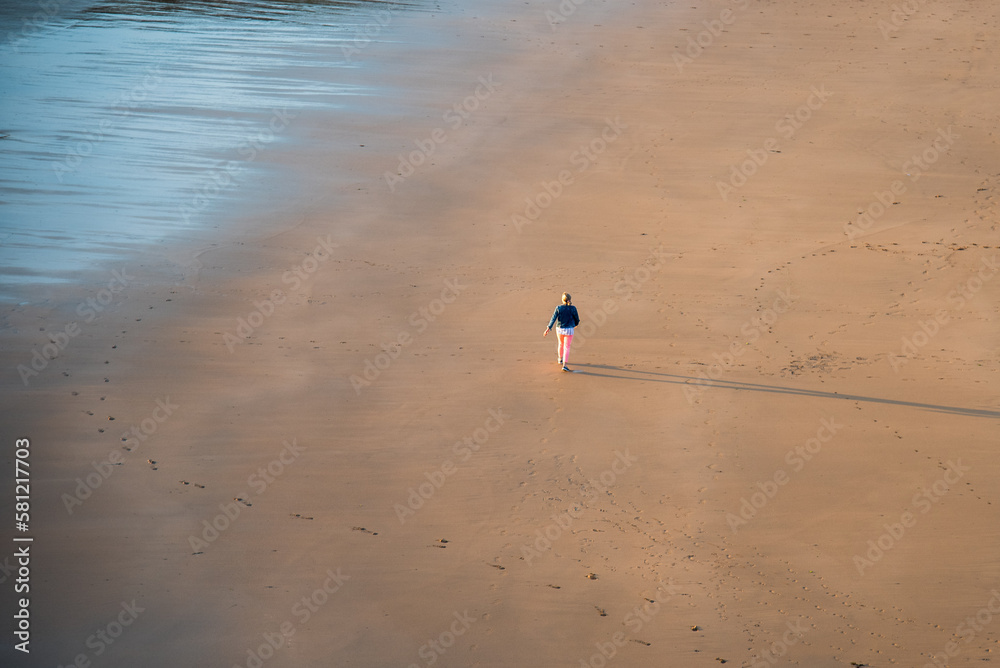Obraz premium Unrecognized person walking on the sandy beach at sunset. Healthy lifestyle. Exercising outdoors