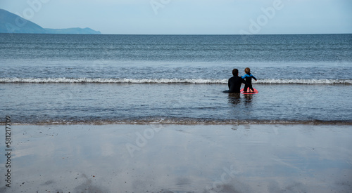Canvas Print Father helping child swimming and surfing in the ocean