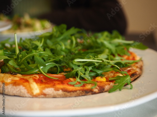 a part of pizza pie with rocket leaves at an Italian restaurant