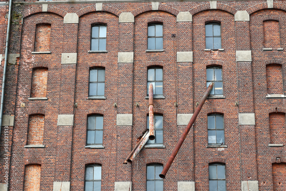 Ceglana ściana starej fabryki w europie z oknami.  - obrazy, fototapety, plakaty 