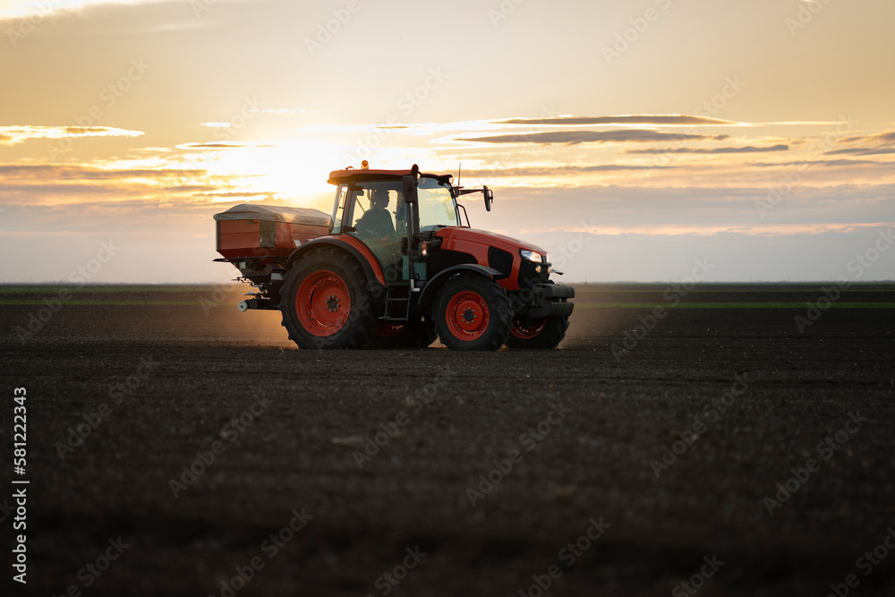 Tractor spreading artificial fertilizers in field Tractor spreading artificial fertilizers in field