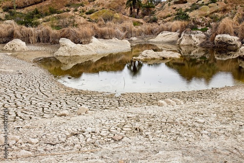 Cracked soil on the shore of a lake that's drying up. Shows climate change.