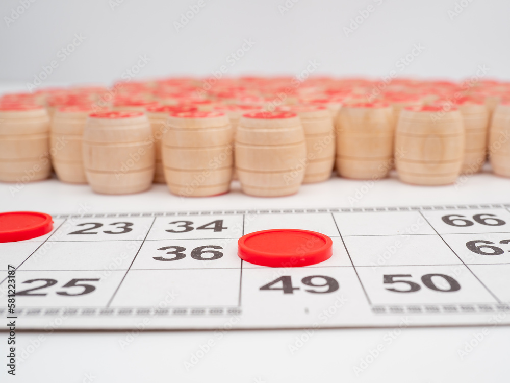 Board game bingo. Wooden barrels with lotto numbers, playing cards for the game. Close-up. Board game bingo. Wooden barrels with lotto numbers, playing cards for the game. Close-up.