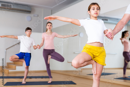 Portrait of focused tween girl practicing yoga asanas with family at yoga studio