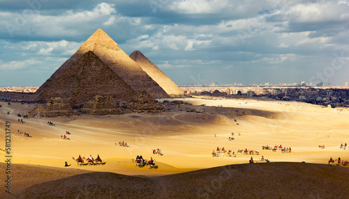 Tourists ride camels on the hills of Giza Plateau near the Great Pyramids. Giza. Western Desert, Giza, Cairo, Egypt