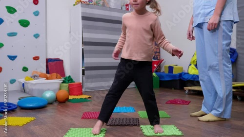 Kid on Sensory Mat Massage during sensory integration session. child girl in rehabilitation centre with physiotherapist doing orthopedic correction. 