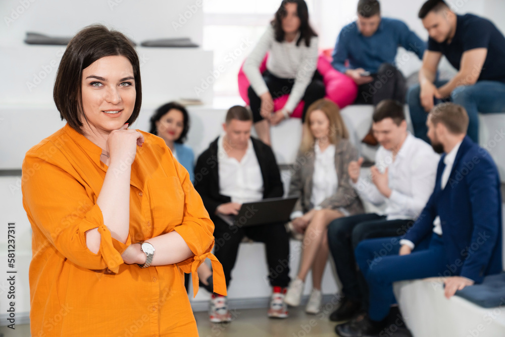 Obraz premium a brunette woman in an orange blouse with men and women in the office.