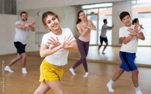 Young girl exercising aerobic dance with her family in gym.