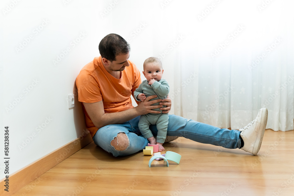 Father sitting on the floor playing with his baby Father sitting on the floor playing with his baby