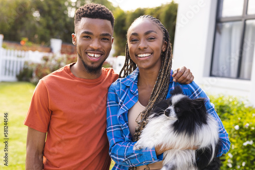 Portrait of happy african american couple holding pet dog and smiling, copy space photo