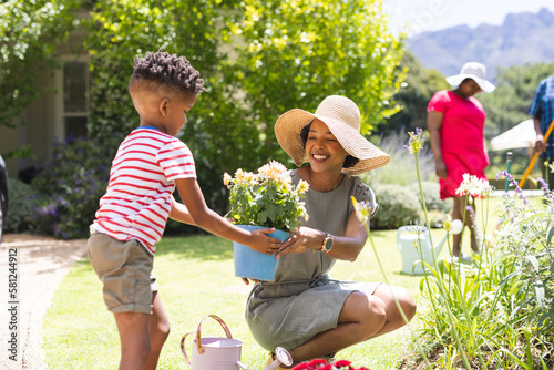 Happy african american family planting flowers in garden