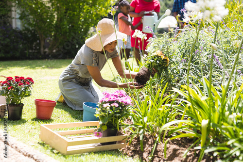 Happy african american family planting flowers in garden