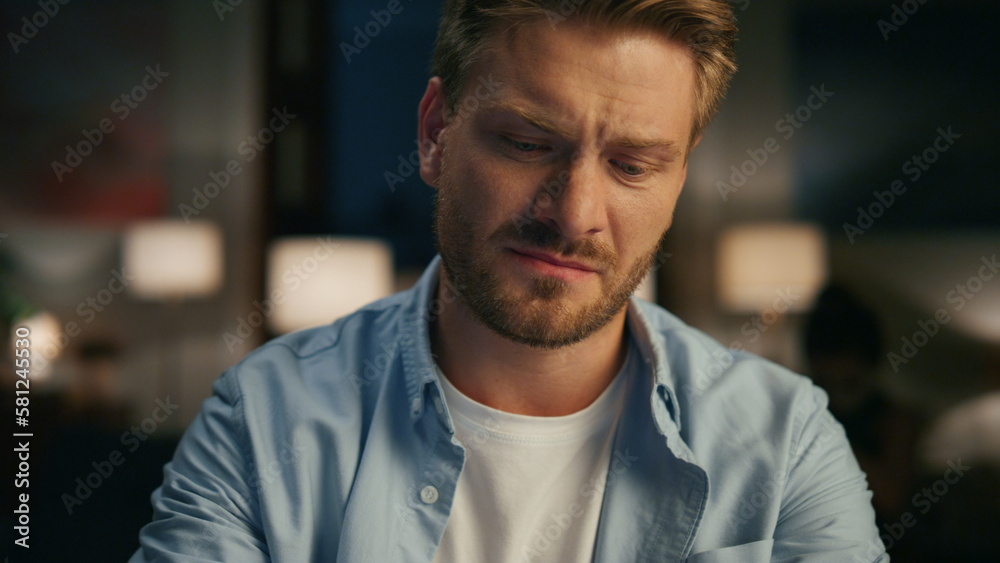 Closeup serious guy ending call at evening flat. Man watching wife rejoicing Closeup serious guy ending call at evening flat. Man watching wife rejoicing
