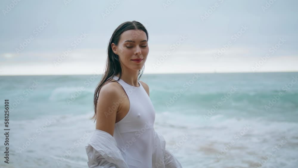 Lady walking cloudy shore in white swimsuit closeup. Woman posing in front ocean Lady walking cloudy shore in white swimsuit closeup. Woman posing in front ocean
