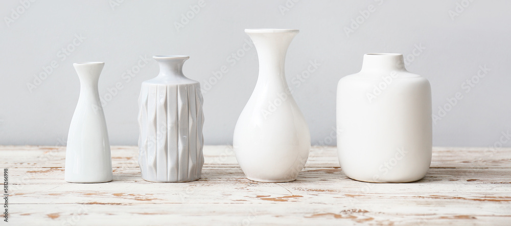 Different white vases on wooden table against light background Different white vases on wooden table against light background