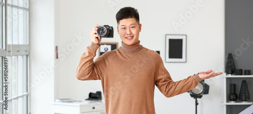 Happy young Asian photographer in modern studio