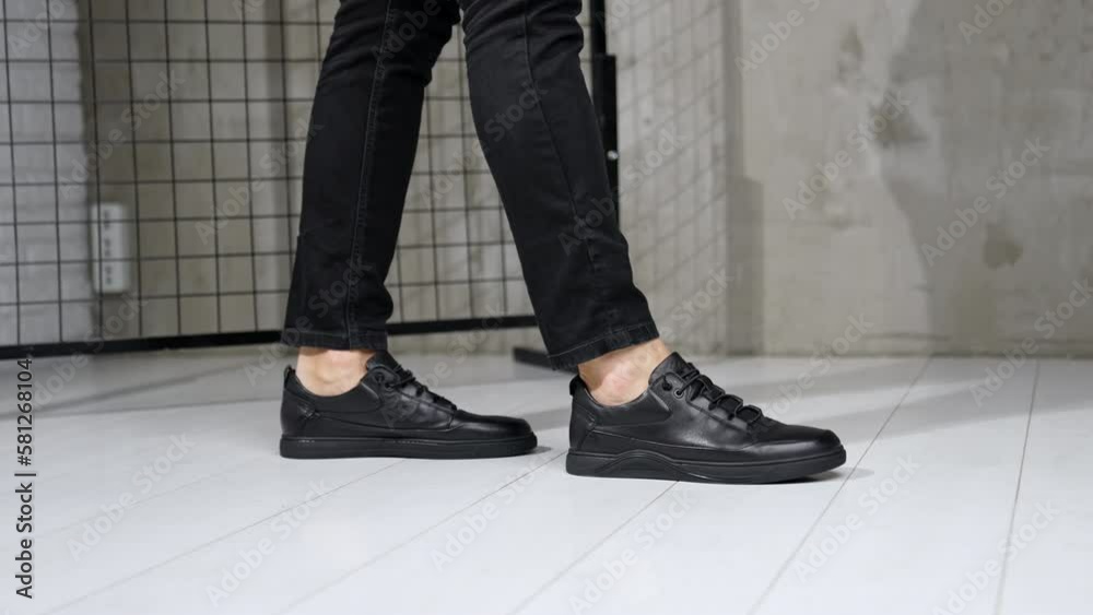 Unrecognized man in black jeans and leather sneakers showing moonwalk. Stylish male footwear demonstration in studio. Unrecognized man in black jeans and leather sneakers showing moonwalk. Stylish male footwear demonstration in studio.