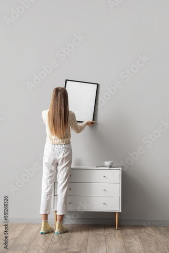 Young woman hanging blank f...