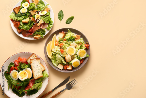 Plates of delicious salads with boiled eggs on beige background