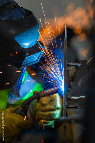 The welder is welding a structural steel with gas metal arc welding ( GMAW ) in the workshop.