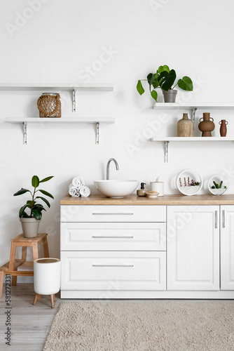 Interior of light bathroom with sink, counters and shelves