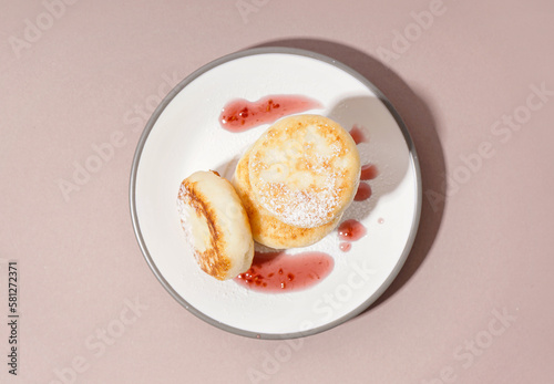 Plate with tasty cottage cheese pancakes and strawberry jam on color background