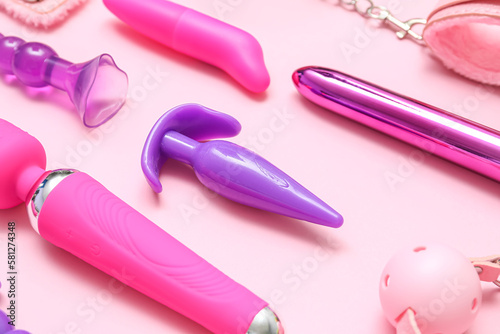 Different sex toys on pink background, closeup