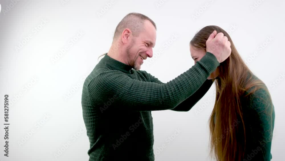 man jokingly takes girl by hair from both sides And hits his head and knee show reception sports school funny situations bad attitude towards woman teach to fight married couple on white background