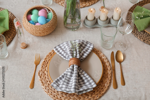 Beautiful Easter table setting with eggs and candles in dining room, closeup